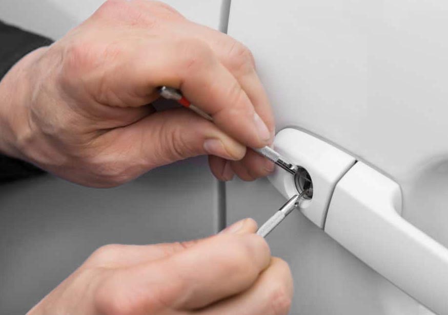 Locksmith opening a locked car door with a specialised tool during a roadside vehicle lockout